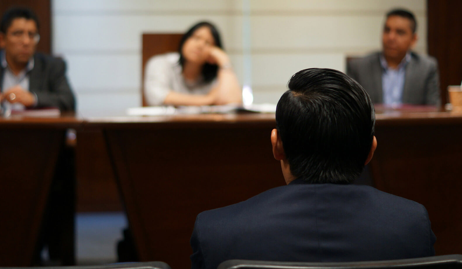 expert-services@2x A male witness in front of a panel of three people. Photo by Saul Bucio on Unsplash